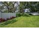 Expansive backyard featuring lush green grass, mature trees, and a well-maintained white fence at 11279 Oakridge Trl, Seminole, FL 33772