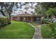 Charming single-story home with a covered porch, a well-manicured lawn, and mature trees at 11279 Oakridge Trl, Seminole, FL 33772
