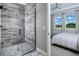 Modern bathroom with a glass shower and a glimpse into a bedroom with a bright window view at 12574 Somatic Ct, Venice, FL 34293