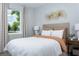Cozy bedroom featuring a soft white comforter, accent pillows, and a sunny window with scenic views at 12574 Somatic Ct, Venice, FL 34293