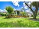 Beautifully landscaped home featuring a lush green lawn, mature trees, and colorful flowering bushes at 15126 Shearcrest Dr, Lithia, FL 33547