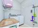 Practical laundry room featuring tile flooring, washer and dryer, overhead racks, and cleaning supplies at 15126 Shearcrest Dr, Lithia, FL 33547