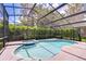 Beautiful screened-in pool and spa surrounded by lush landscaping and a dark metal enclosure at 15126 Shearcrest Dr, Lithia, FL 33547