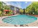 Community pool surrounded by lush landscaping, lounge chairs, and orange umbrellas at 501 S Moody Ave # 1134, Tampa, FL 33609