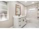Modern bathroom featuring marble tile, a wood-trimmed mirror, and a white vanity with black hardware at 5092 Abagail Dr, Spring Hill, FL 34608