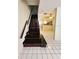 Tiled floors lead to a staircase with dark wooden steps and access to the kitchen at 6620 121St Ave # 1, Largo, FL 33773