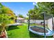 Spacious backyard featuring artificial grass, a trampoline, and play equipment at 12351 Cloverstone Dr, Tampa, FL 33624
