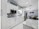 Modern white kitchen with gray backsplash, stainless steel appliances and quartz countertops at 12351 Cloverstone Dr, Tampa, FL 33624