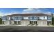 Modern townhome exterior featuring a blue and white facade, garage, and neatly maintained landscaping at 13240 Stable Pl, Parrish, FL 34219