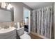 Cozy bathroom with a shower featuring a decorative curtain, a sink, and a toilet at 1453 Belleair Rd, Clearwater, FL 33756