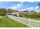 Quaint single-story home showcasing a neatly fenced yard and lush landscaping under a sunny sky at 1453 Belleair Rd, Clearwater, FL 33756