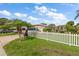 Single-story home with a white picket fence, lush green lawn, and palm trees enhancing its curb appeal at 1453 Belleair Rd, Clearwater, FL 33756