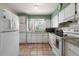 Well-lit kitchen with white appliances and cabinets, granite countertops, and tile flooring at 1453 Belleair Rd, Clearwater, FL 33756