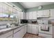 Functional kitchen with tiled countertops and floors, white cabinets, and natural light from the window at 1453 Belleair Rd, Clearwater, FL 33756