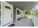 View of the covered front porch with stone accents, white railing, and a cozy bench at 2612 Lenna Ave, Seffner, FL 33584