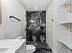 Bright bathroom featuring black marble accent wall in shower, floating shelves and modern toilet at 3909 W Oklahoma Ave, Tampa, FL 33616