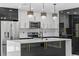 A modern kitchen featuring an island, stainless steel appliances, and stunning, stylish lighting at 3909 W Oklahoma Ave, Tampa, FL 33616