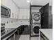 Modern kitchen featuring stainless steel appliances and black and gold accents with stacked laundry units at 3909 W Oklahoma Ave, Tampa, FL 33616