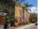 Exterior view of a multi-story condo building with bright colors, landscaping, and palm trees on a sunny day at 4207 S Dale Mabry Hwy # 6212, Tampa, FL 33611