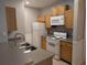 Kitchen with stainless steel sink, white appliances, light wood cabinets, and grey countertops at 4207 S Dale Mabry Hwy # 6212, Tampa, FL 33611