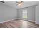 Clean bedroom featuring a ceiling fan, wood-look floors, a window and white trim at 6103 Fairway Dr, Ridge Manor, FL 33523