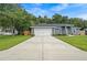 Exterior view of a charming home featuring a large driveway and a well-maintained lawn at 6103 Fairway Dr, Ridge Manor, FL 33523