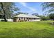 Exterior view of a brick home with a large lawn and white picket fence, surrounded by mature trees at 11301 Donneymoor Dr, Riverview, FL 33569