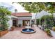 Charming courtyard with brick paving, a central fountain, lush greenery, and seating, perfect for relaxation and entertaining at 11503 Robles Del Rio Pl, Temple Terrace, FL 33617