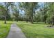Scenic park view with a walking path, lush green grass, and mature trees, perfect for outdoor recreation at 11503 Robles Del Rio Pl, Temple Terrace, FL 33617