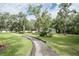 Scenic view of a walkway winding through a community park with mature trees and cabana at 11503 Robles Del Rio Pl, Temple Terrace, FL 33617