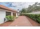 Paver patio outside with double doors, a red-tile roof, and a privacy hedge at 11503 Robles Del Rio Pl, Temple Terrace, FL 33617