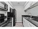 Galley kitchen featuring modern black appliances, granite countertops, and white cabinets at 12336 Villager Ct, Tampa, FL 33625