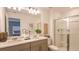 Bathroom with double sink vanity, a large mirror, and walk-in shower with glass doors at 13236 Stable Pl, Parrish, FL 34219