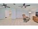 Open living room with tile floors, dual ceiling fans, and a cozy reading nook featuring a recliner and accent table at 1708 Pond Lake Dr, Tampa, FL 33612