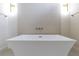 Modern white bathtub with stylish textured tile backdrop and brushed gold fixtures at 1808 W Erna Dr, Tampa, FL 33603