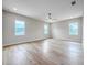 A spacious bedroom featuring hardwood floors, natural light from three windows, and a ceiling fan at 1808 W Erna Dr, Tampa, FL 33603