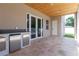 Outdoor kitchen featuring stainless steel appliances, a stone counter, and travertine flooring at 1808 W Erna Dr, Tampa, FL 33603