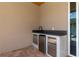 A stone countertop with a sink, black faucet, and stainless steel appliances in an outdoor kitchen at 1808 W Erna Dr, Tampa, FL 33603