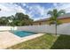 Tranquil pool featuring travertine surround, a white fence, and lush landscaping, creating a private backyard oasis at 1808 W Erna Dr, Tampa, FL 33603
