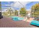 Screened-in pool surrounded by brick patio, tropical landscaping, and lounge chairs at 22623 Cliffside Way, Land O Lakes, FL 34639
