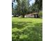 Spacious backyard with lush green grass and mature trees, featuring a convenient covered carport for vehicles at 4106 Old Mulberry Rd, Plant City, FL 33567