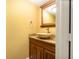 Powder room with round vessel sink, granite countertop, wood vanity, and decorative mirror at 4117 Daventry Ln, Palm Harbor, FL 34685