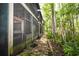 Exterior of the home featuring a pathway leading to a screened-in porch and lush greenery at 4117 Daventry Ln, Palm Harbor, FL 34685