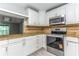 Kitchen featuring white cabinets, granite countertops, stainless steel appliances, and light grey vinyl floors at 4117 Daventry Ln, Palm Harbor, FL 34685