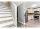 Open floor plan showing kitchen with stainless refrigerator, white cabinets, and staircase to upper level at 4117 Daventry Ln, Palm Harbor, FL 34685