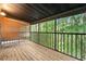 A screened-in patio with wood floors, bamboo blinds, and a view of a lush, green forest at 4117 Daventry Ln, Palm Harbor, FL 34685