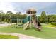 Community playground area featuring slides, climbing structures, and swings surrounded by lush greenery at 4117 Daventry Ln, Palm Harbor, FL 34685