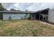Backyard featuring the rear of the house, a utility shed with covered area, and a mix of green and dry grass at 4209 E Hanna Ave, Tampa, FL 33610