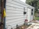 Exterior view of white metal shed with door and window, bordered by a brick paver path at 4209 E Hanna Ave, Tampa, FL 33610