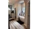 Bright bathroom featuring a soaking tub with black fixtures, framed by monochromatic wall tiles and luxury vinyl flooring at 4217 Balington Dr, Valrico, FL 33596